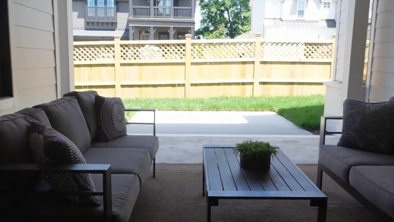 Covered patio with chairs table concrete slab fenced yard and grass