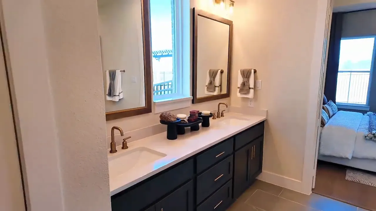 Primary bathroom double vanity with mirrors and gold faucets in new construction home