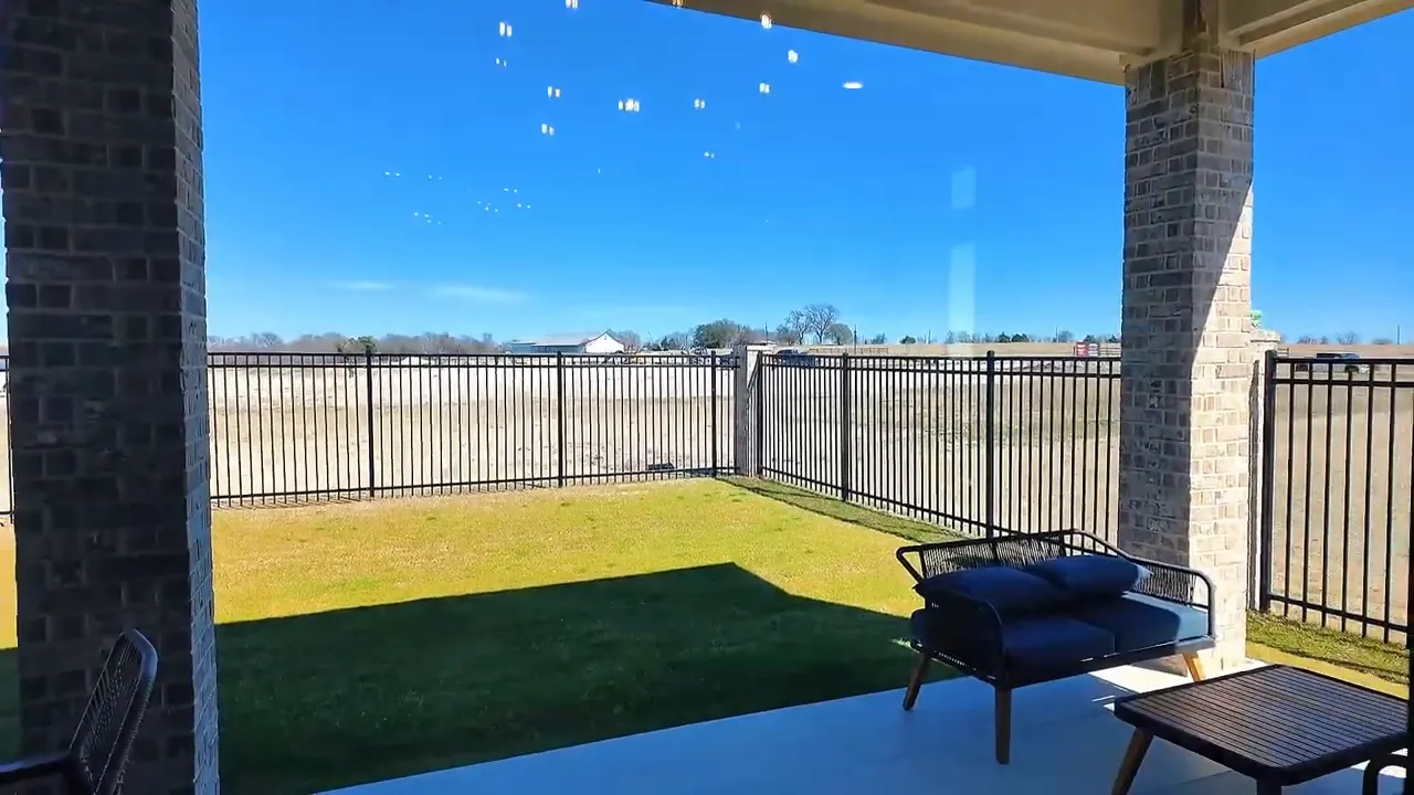 Covered patio with blue seating overlooking a fenced grassy backyard