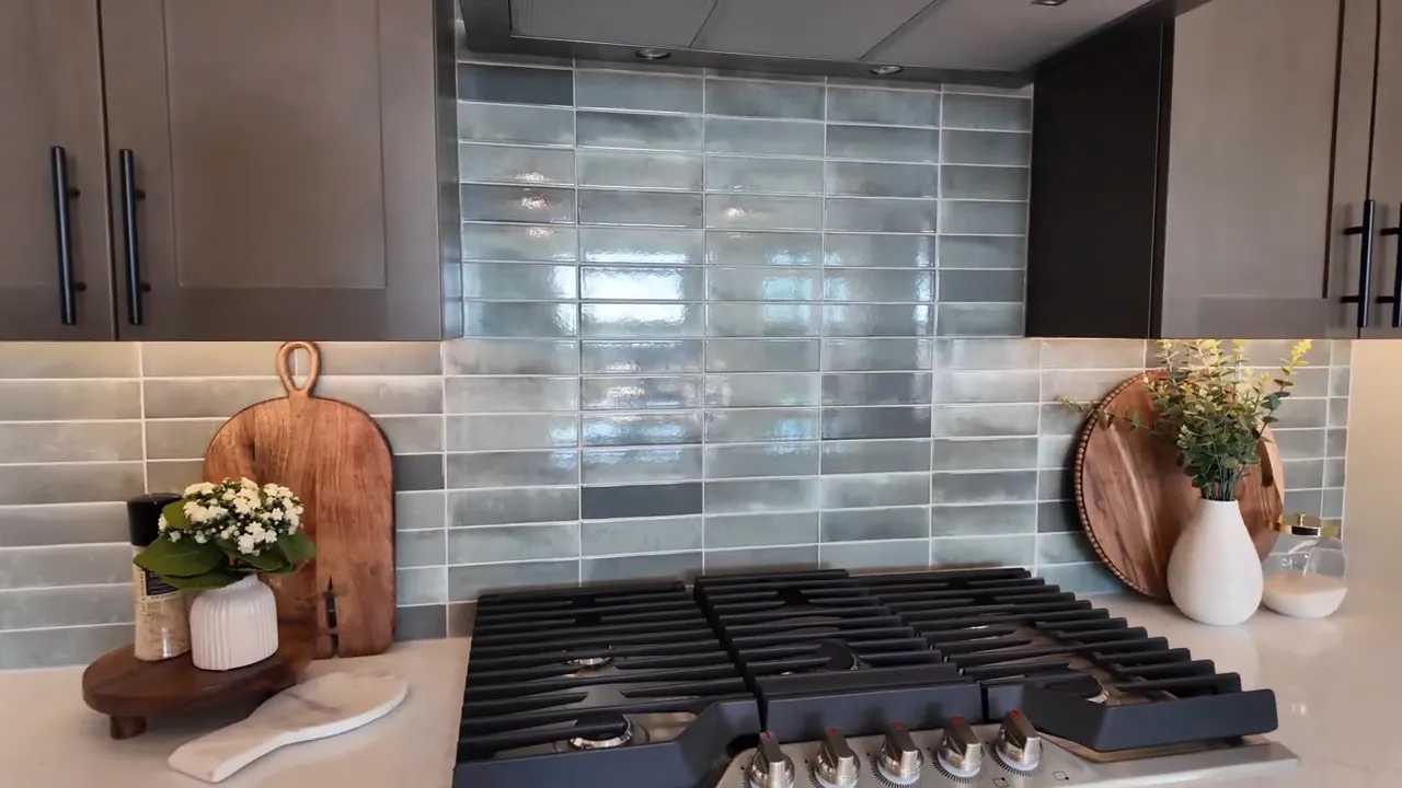 Six burner gas range with tiled backsplash and dark cabinets