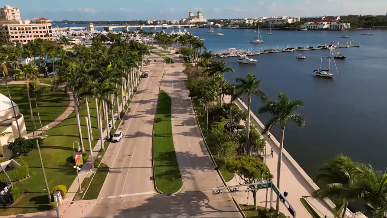 Aerial view of West Palm Beach waterfront road, marina, and palm trees