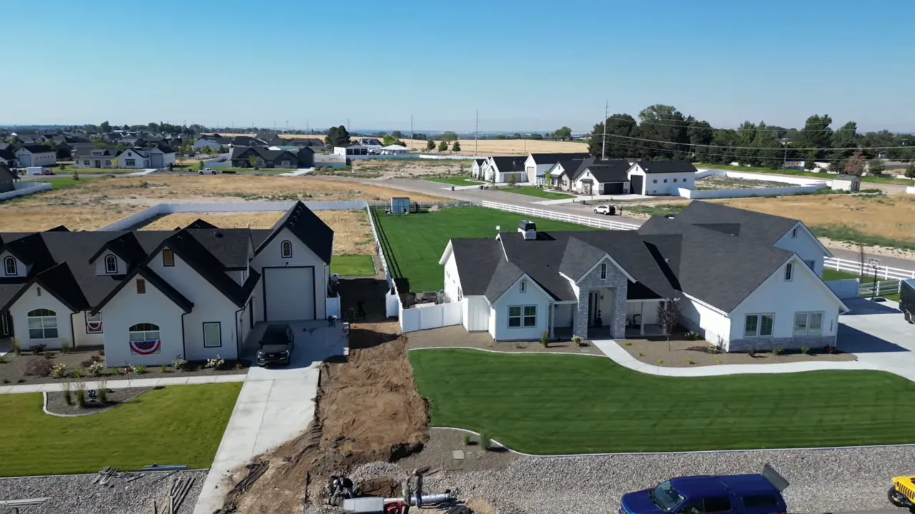 Aerial view of large modern homes beside a pond and open fields
