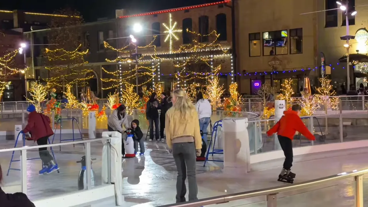 People ice skating outdoors beneath lights in a downtown plaza