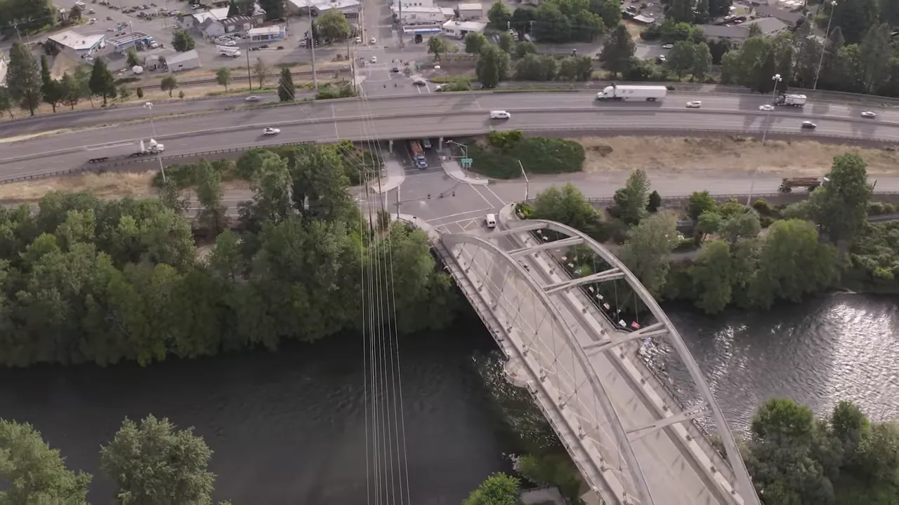 Aerial view of a bridge crossing Rogue River with highways and nearby neighborhoods