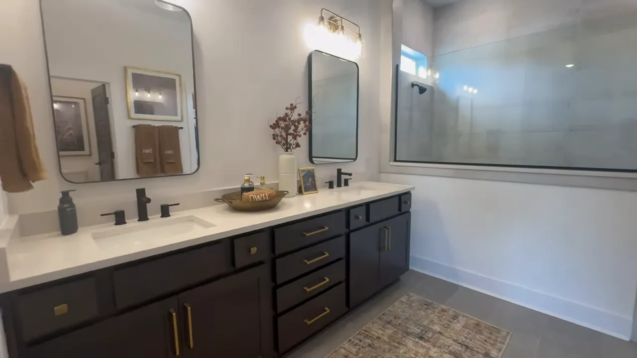 Primary bathroom with double vanity dark cabinets and large shower enclosure
