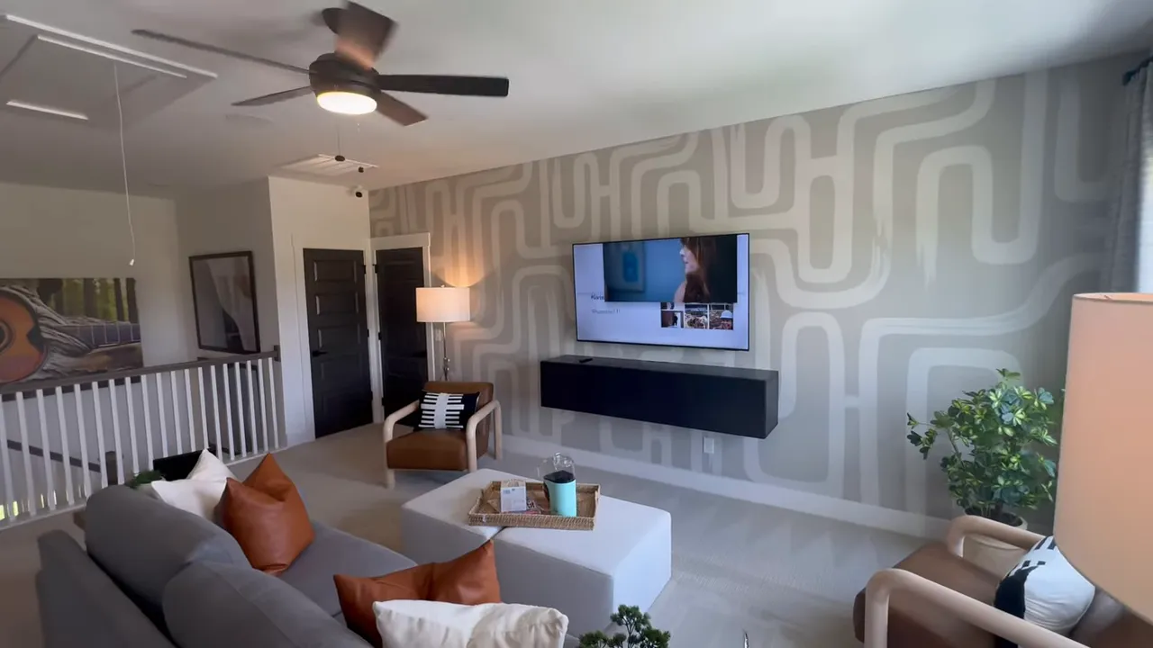 Upstairs bonus room with sofa, chairs, coffee table, and patterned accent wall