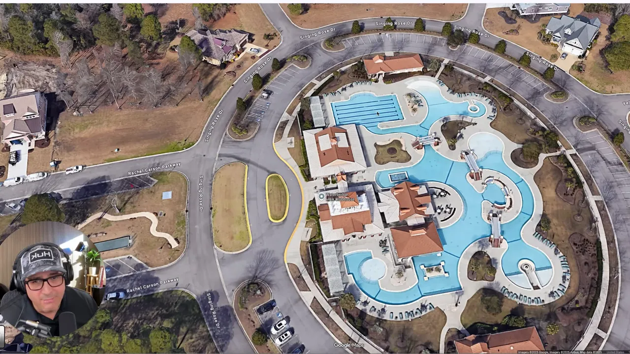 Bird's-eye aerial of a resort-style clubhouse and expansive multi-pool complex with surrounding parking and landscaping; small presenter inset