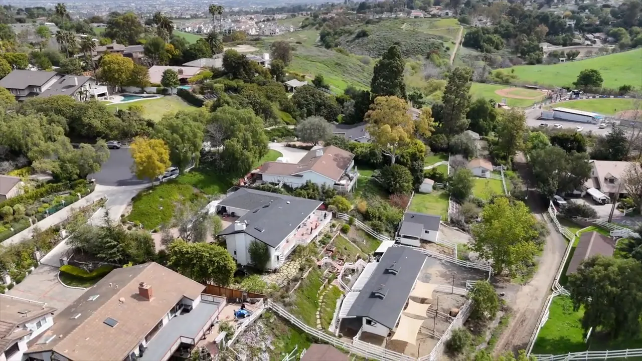 Aerial view of large homes, gardens, wide lots, and green open space