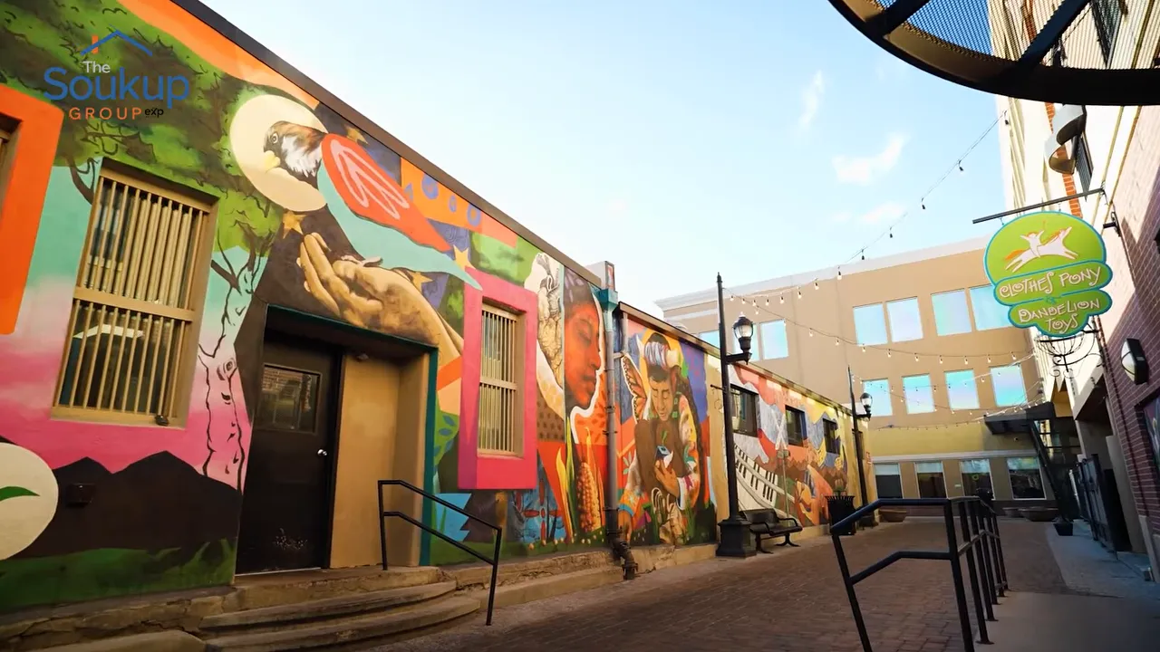 People walking beside colorful murals in a brick alley in Fort Collins