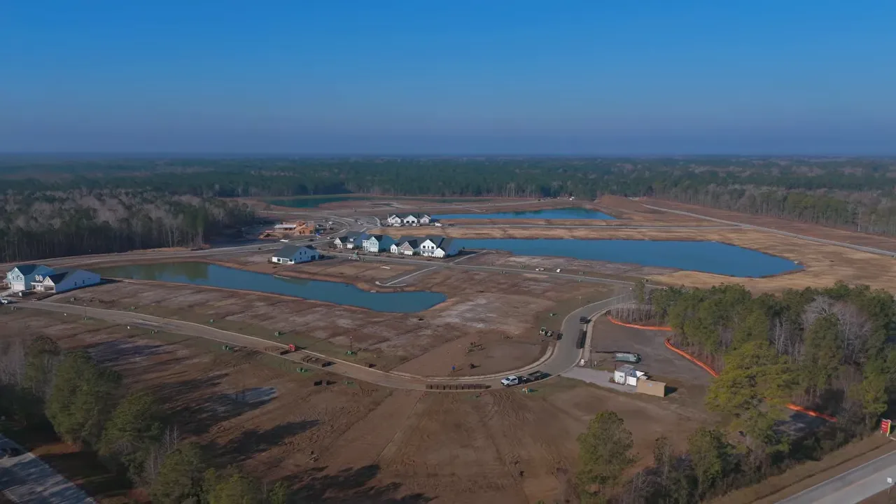 Aerial drone view of Marshfield neighborhood showing homes, roads, and lagoon-style water features