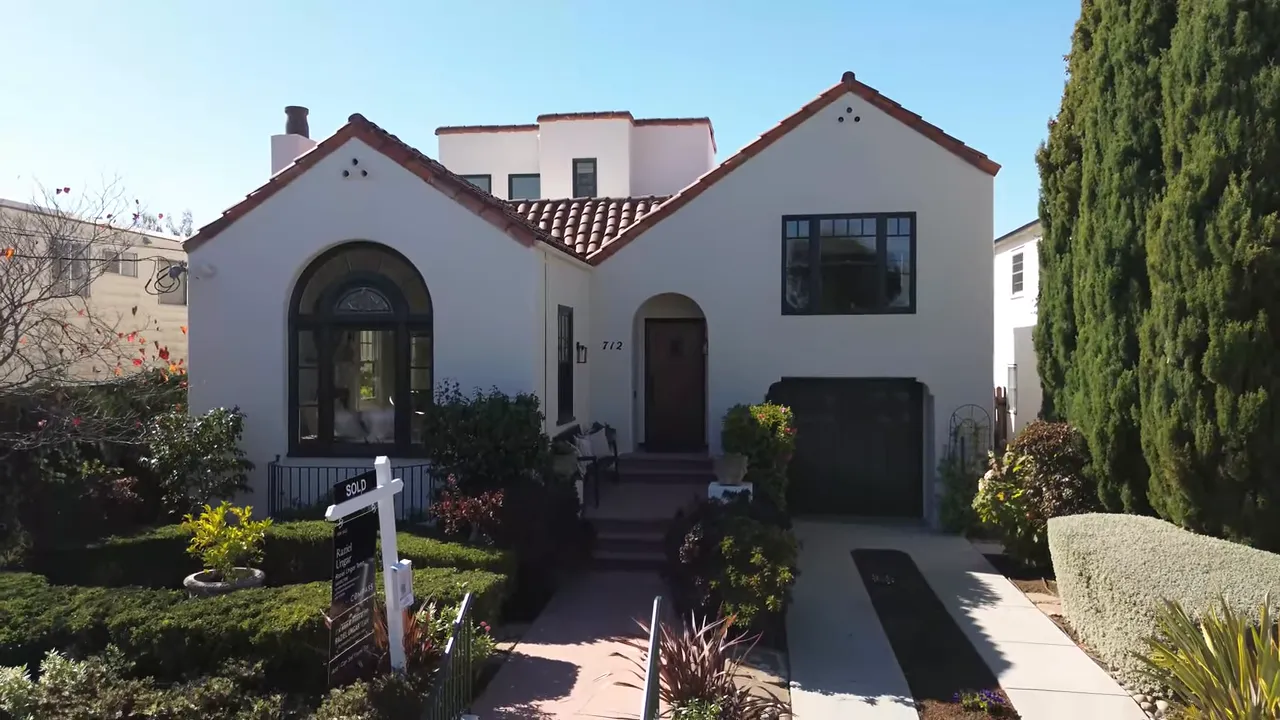 Spanish colonial revival house with red tile roof, arched front window, steps to entry and attached garage