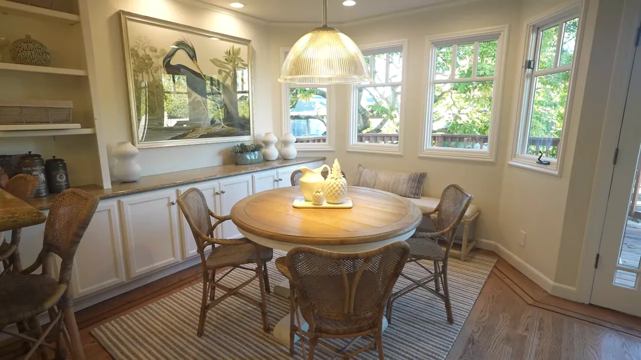 Breakfast nook with round wooden table, wicker chairs and bay windows