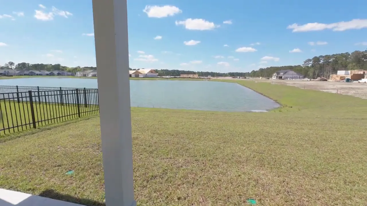 Covered back porch looking out over fenced yard and pond view