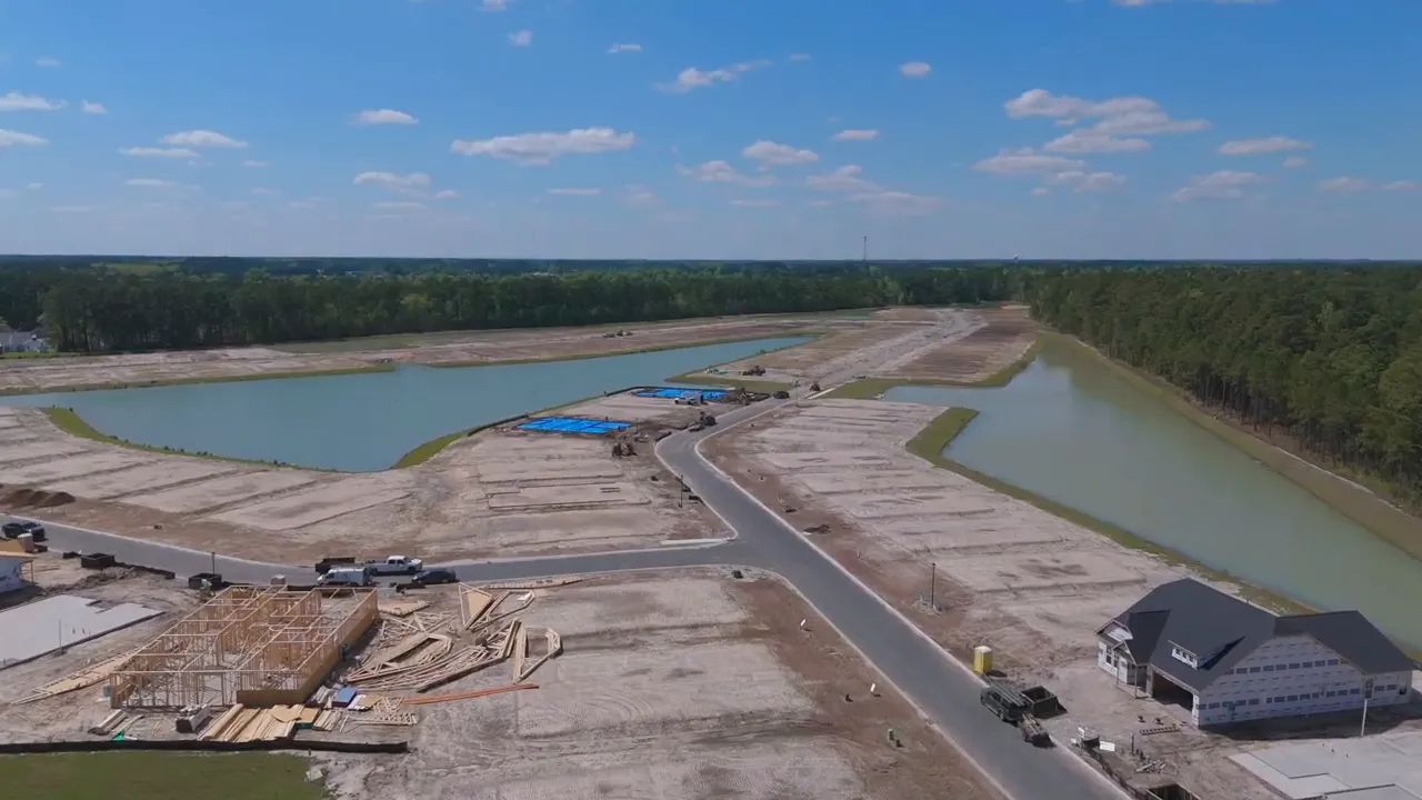 Aerial view of final phase lots under development beside pond and completed homes