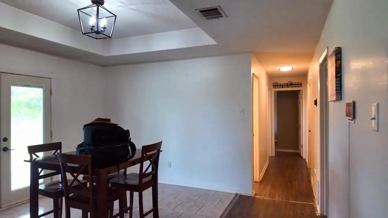 Dining area with tray ceiling light fixture table and chairs beside hallway and french doors