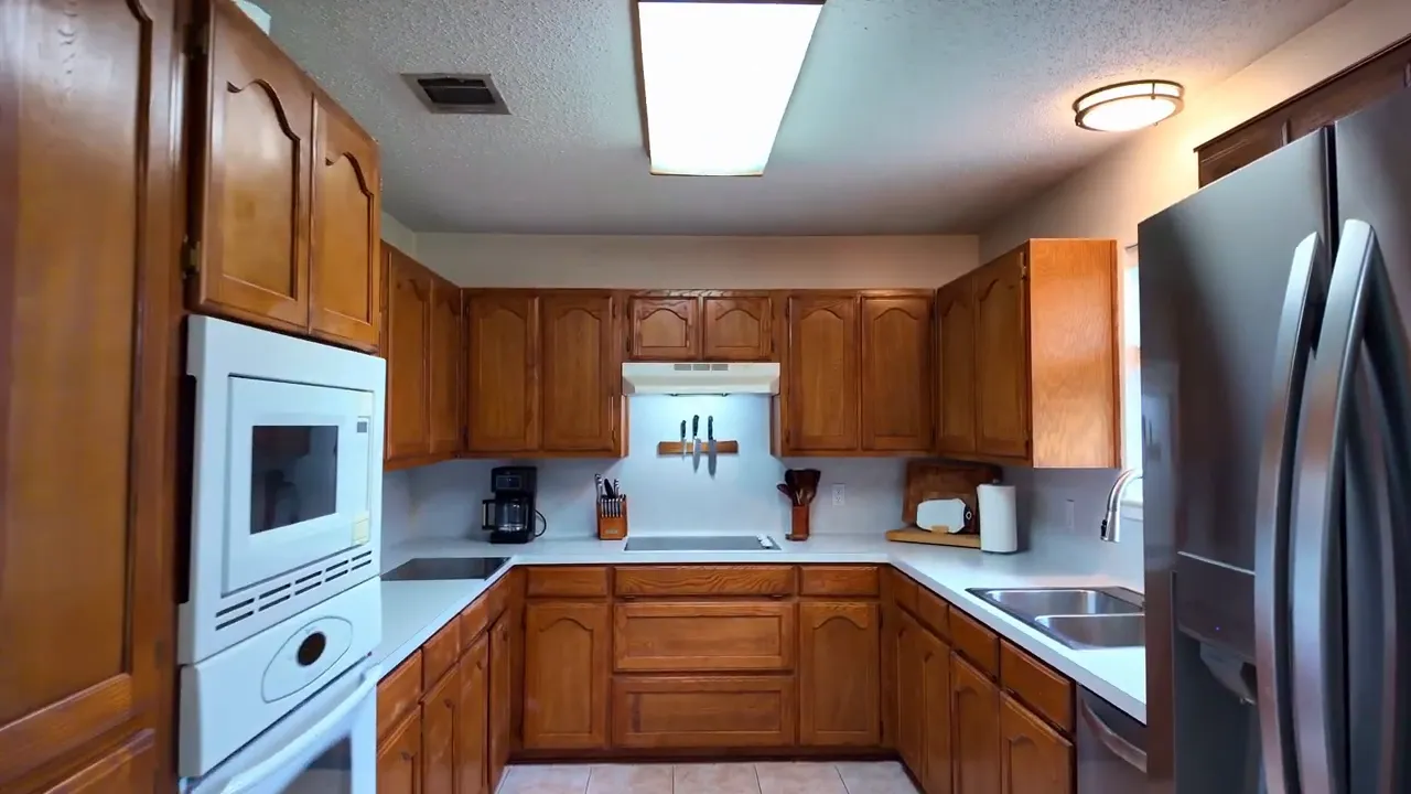Kitchen with extensive wood cabinets white counters built in oven and stainless refrigerator