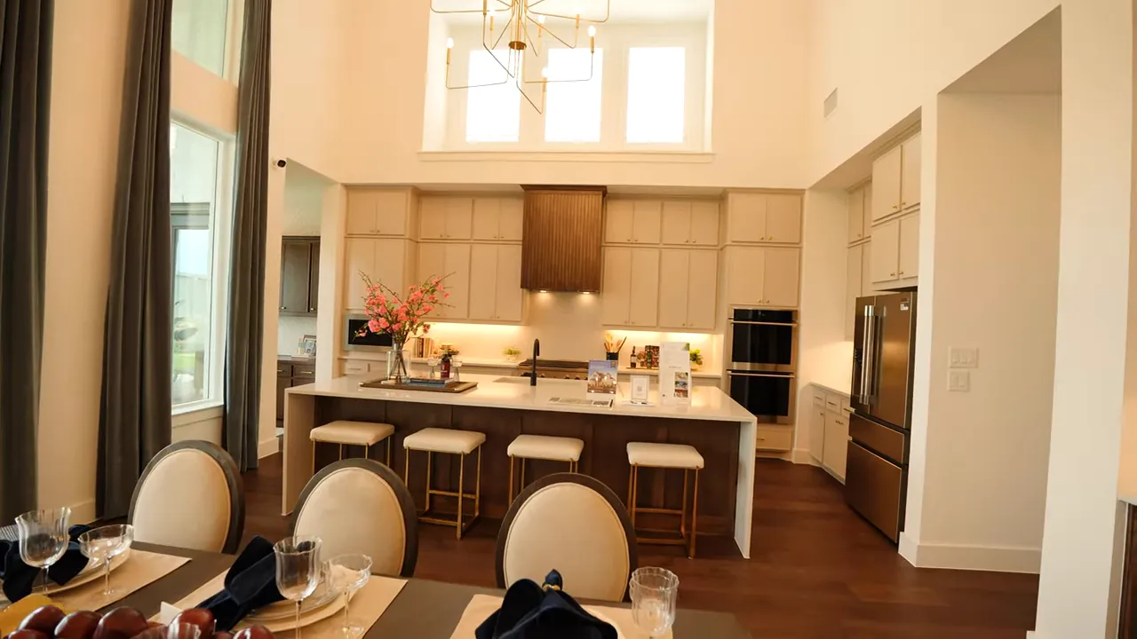 Kitchen with long island light cabinets dark vent hood and upper windows