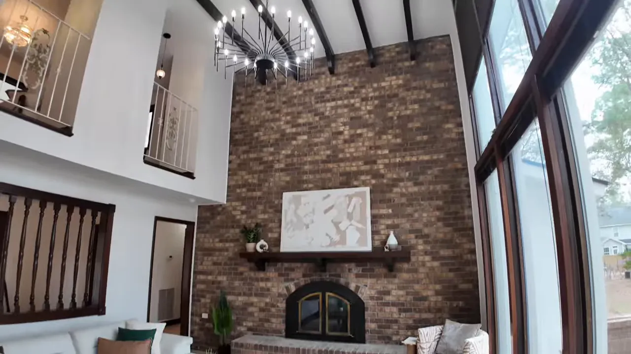Vaulted two-story living room with brick fireplace wall and chandelier