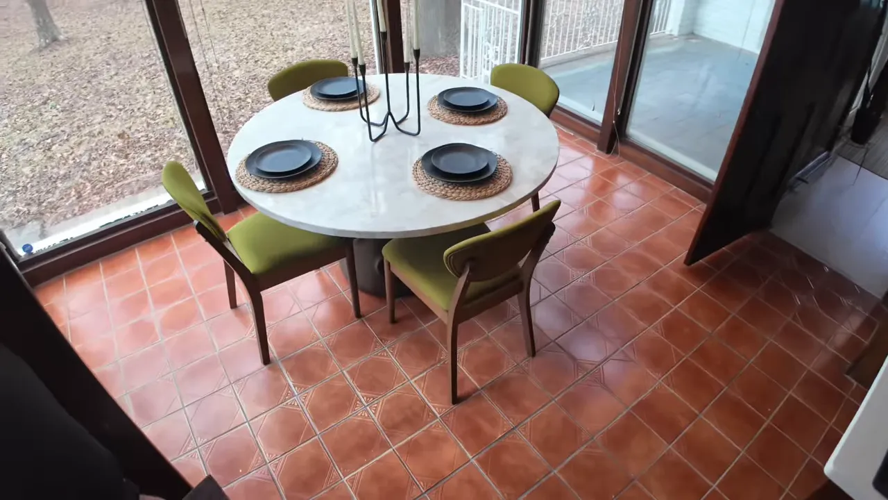 Covered outdoor dining area with round table, chairs, and glass doors at a gated Summerville estate