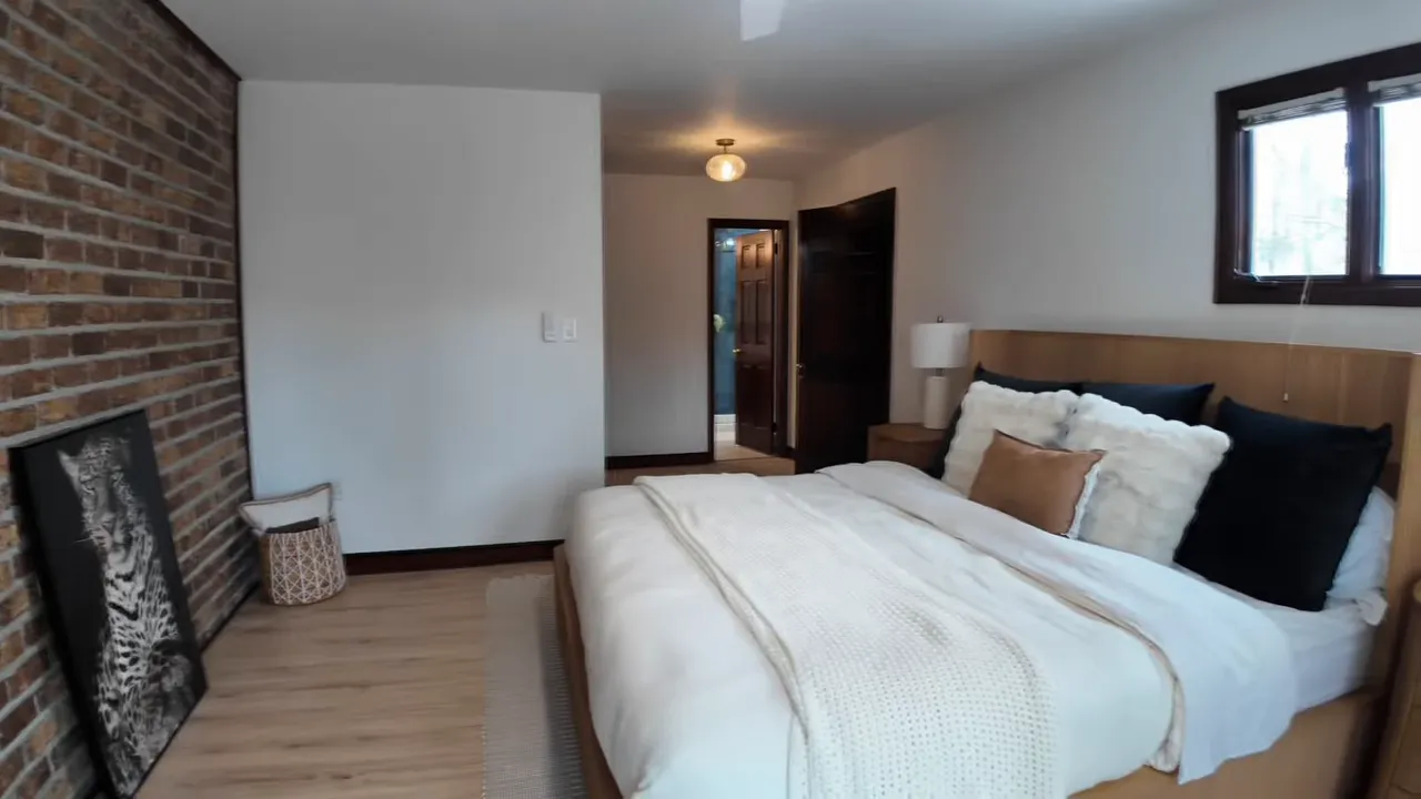 First-floor primary bedroom with brick feature wall and built-in wood paneling in a 1965 Summerville SC home