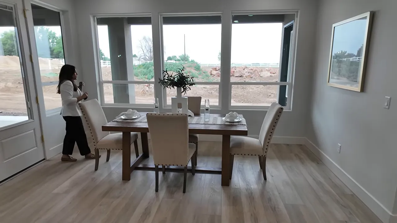Dining room with table surrounded by large windows overlooking the unfinished acreage