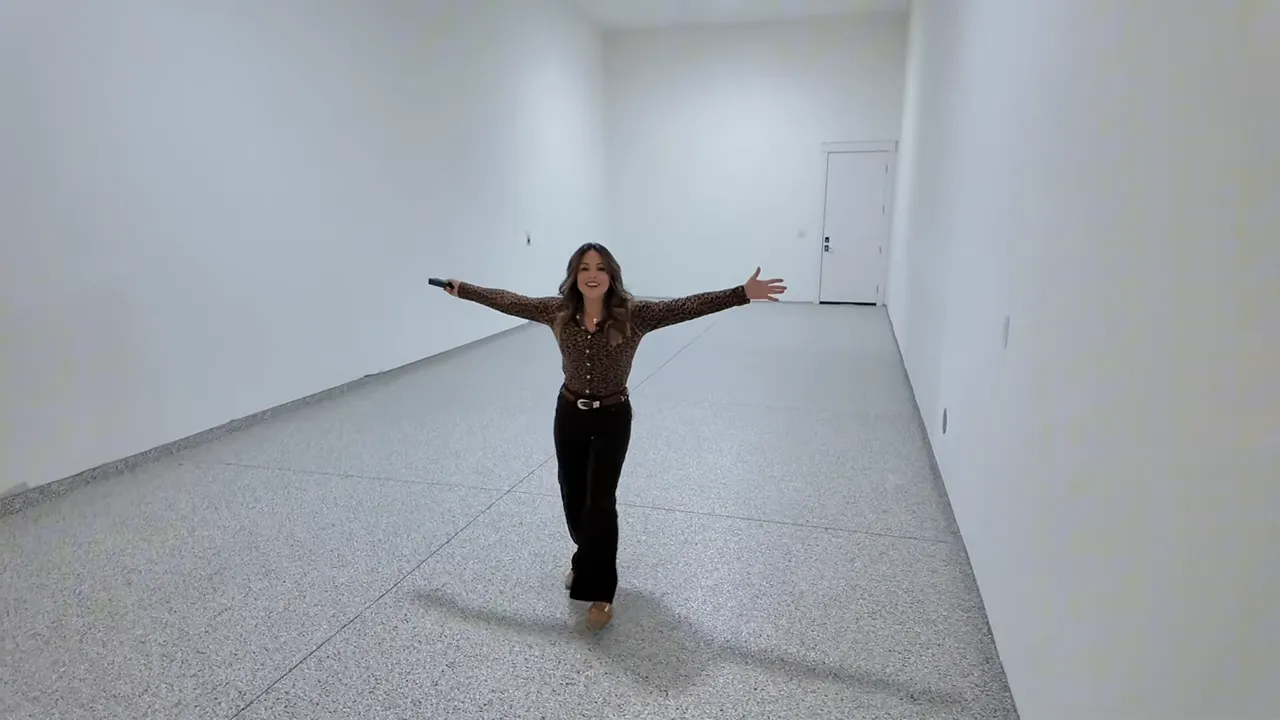 Presenter standing in a long finished garage/RV bay with arms outstretched to show the length and epoxy floor