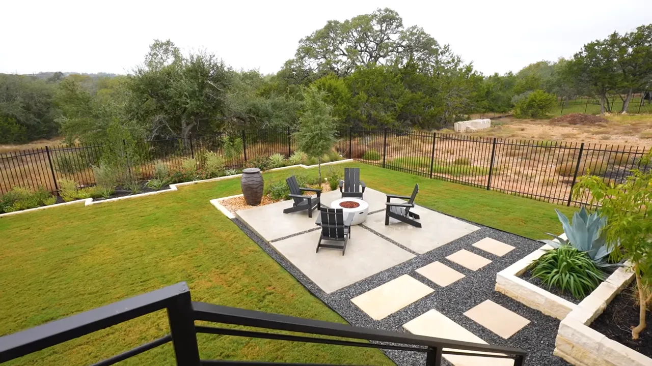Backyard patio with fire pit, seating, stepping stones and iron-rail fence backing to hill country greenbelt