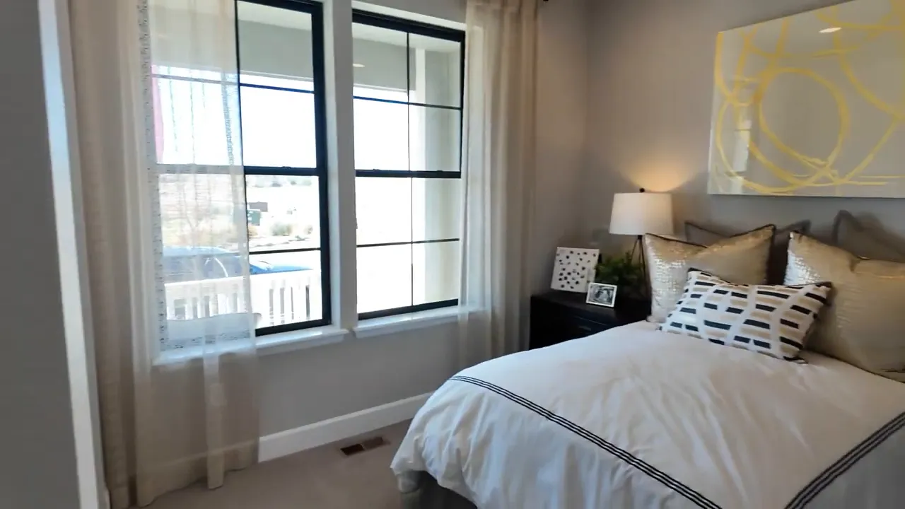 Staged bedroom with large window and modern decor inside the Richmond Arlington home at Independence subdivision in Elizabeth, Colorado