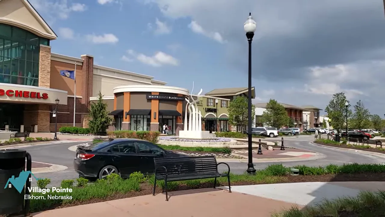 Village Pointe shopping district with storefronts benches and cars in Elkhorn