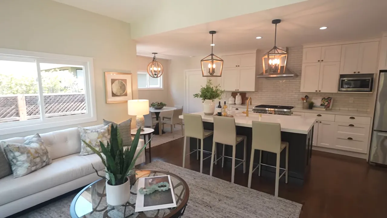 Open kitchen and living area with white cabinets large island bar stools and seating area