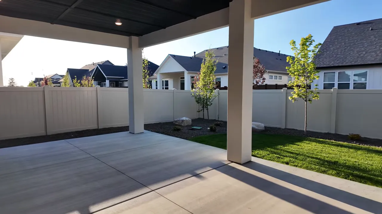 Large covered patio beside small fenced grass backyard