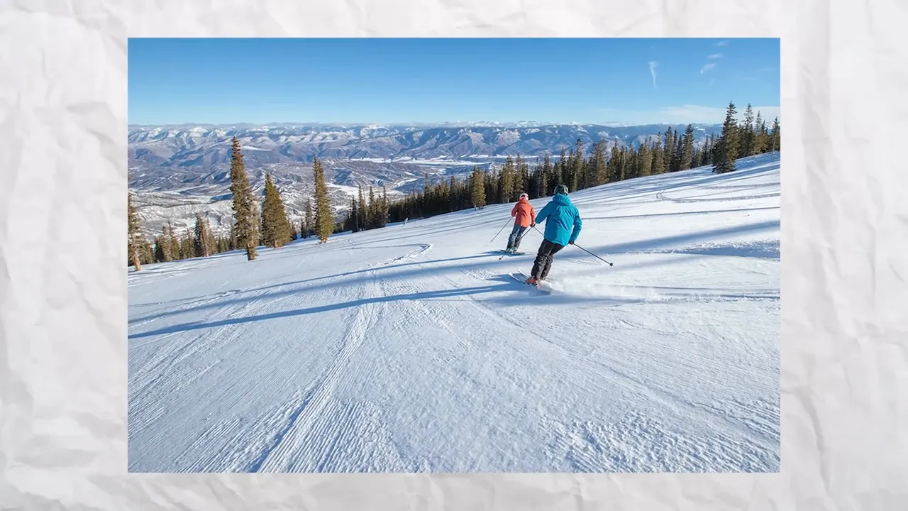 Skiers on a snowy mountain slope overlooking valleys and forested peaks