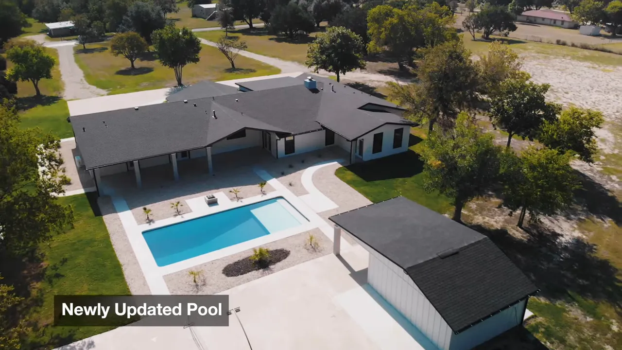 aerial close-up of renovated pool with pool deck and detached cabana at modern ranch