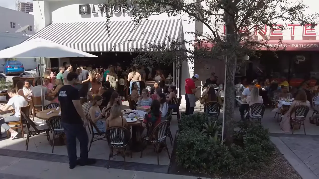 People dining outdoors at a busy restaurant patio in West Palm Beach