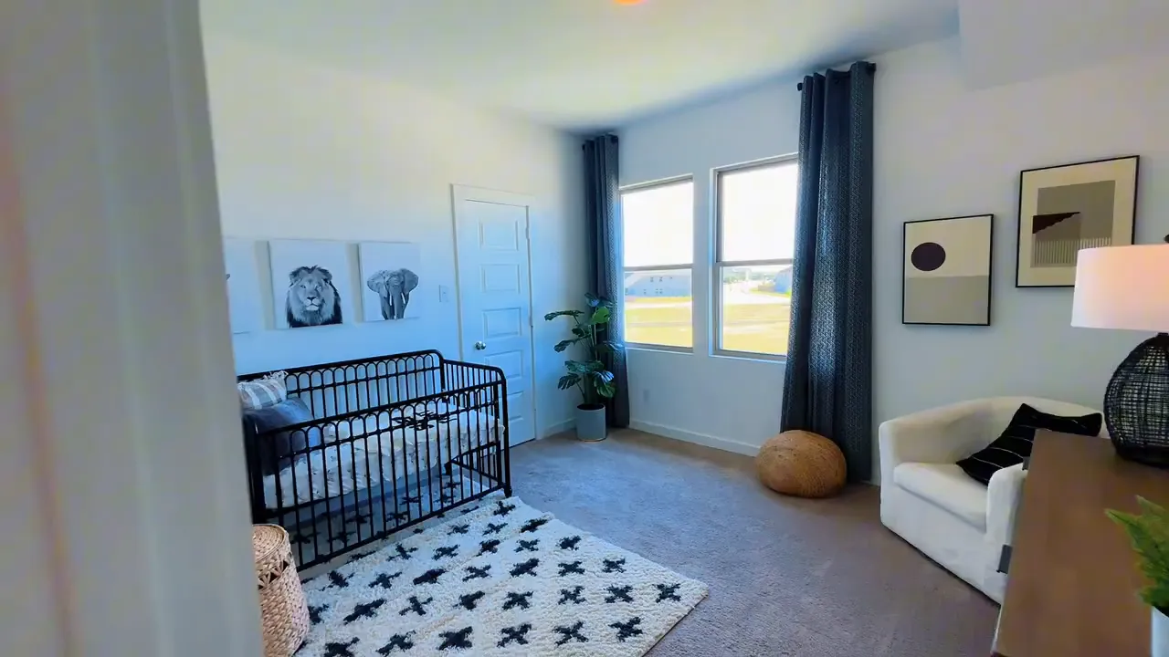 Secondary bedroom staged as nursery with crib rug chair and window
