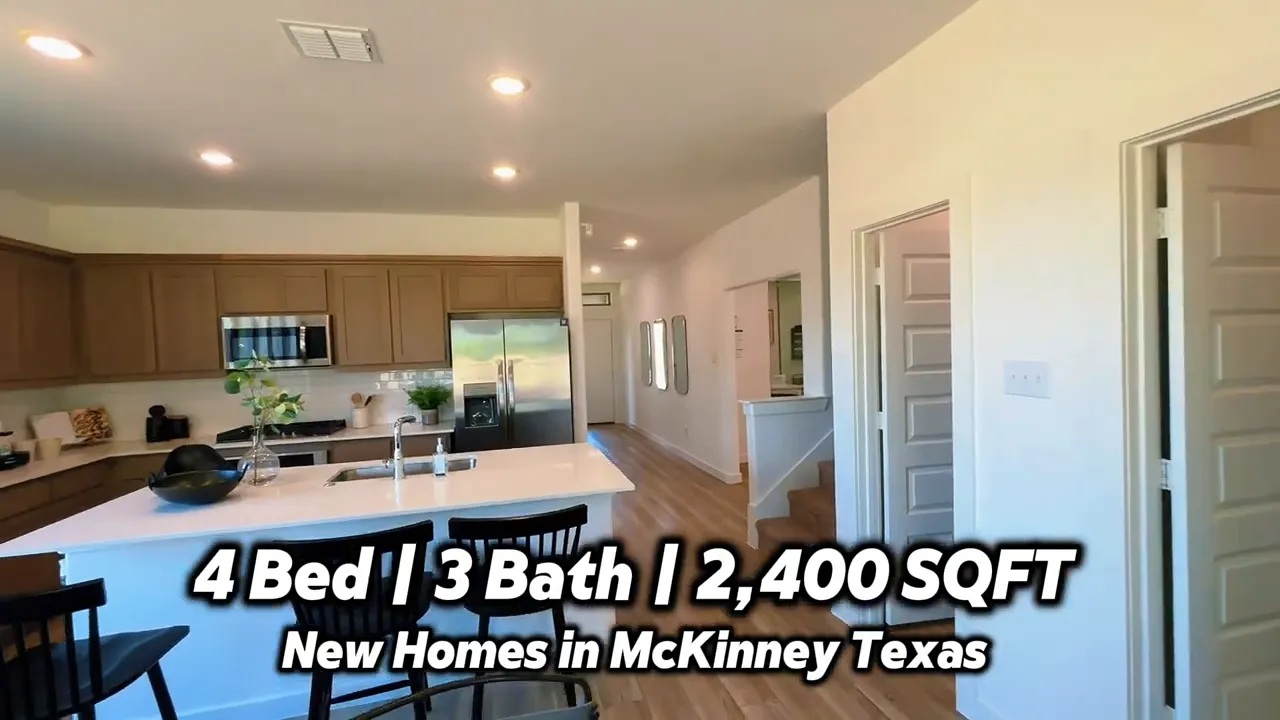 Open kitchen with large island bar stools wood cabinets stainless steel appliances and stairs nearby