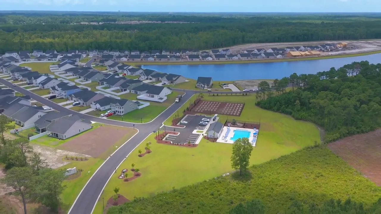 Drone photo of a new housing subdivision with lake, community pool, parking area and visible build sites
