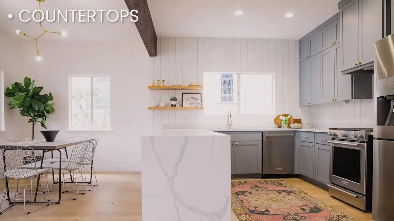 Modern kitchen with large island, gray shaker cabinets, under-cabinet lighting, and stainless appliances