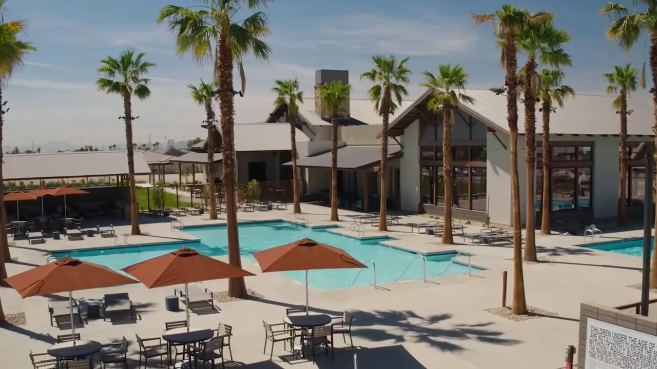 Pool deck with palm trees umbrellas and clubhouse buildings at North Ranch