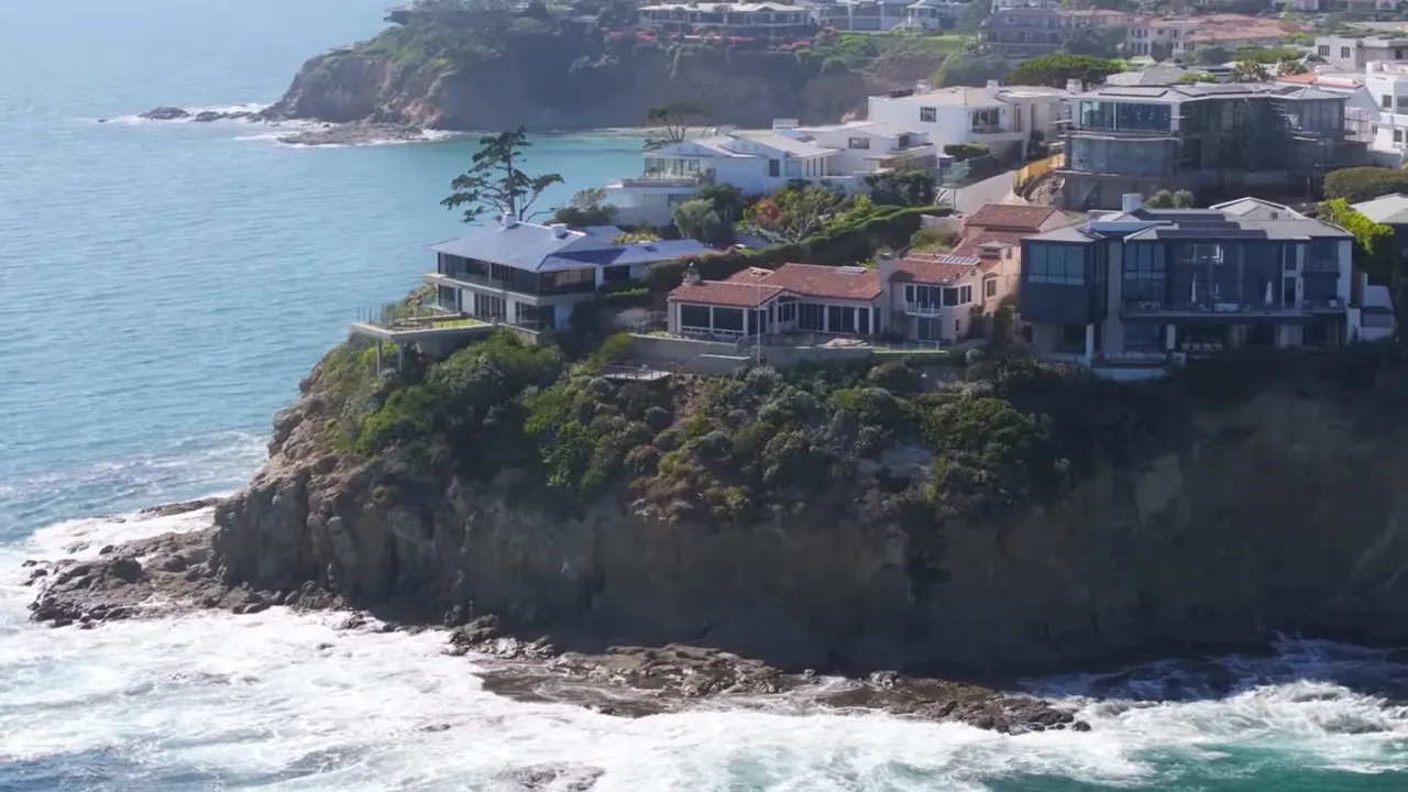 Oceanfront homes sitting on a bluff above crashing waves