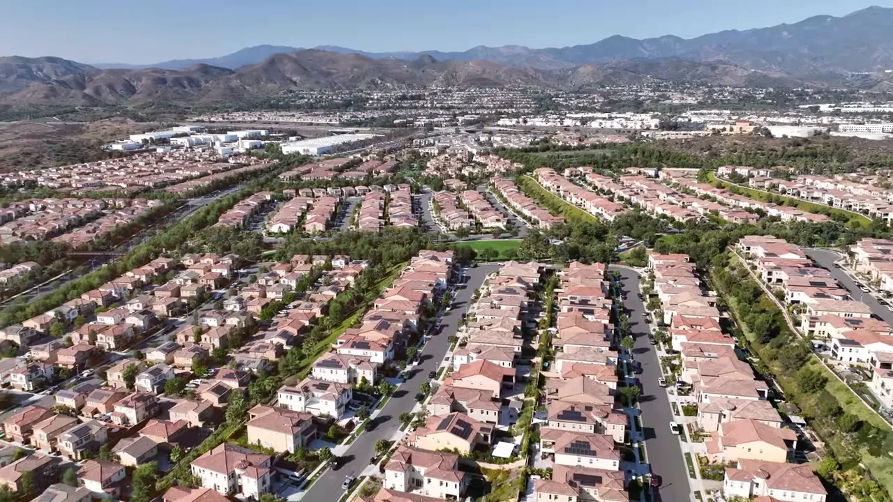 Wide aerial view of dense planned Irvine neighborhood with mountains in the distance