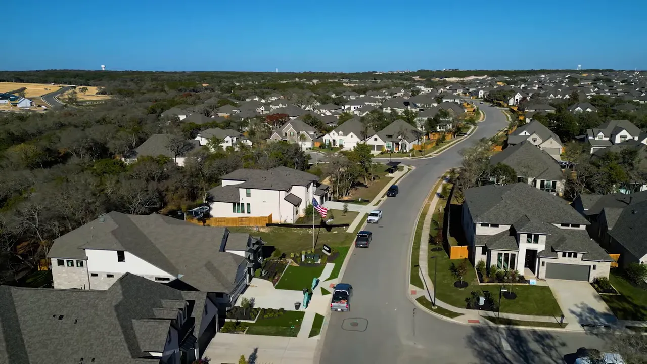 Aerial neighborhood street with new suburban homes and yards in an Austin‑area community