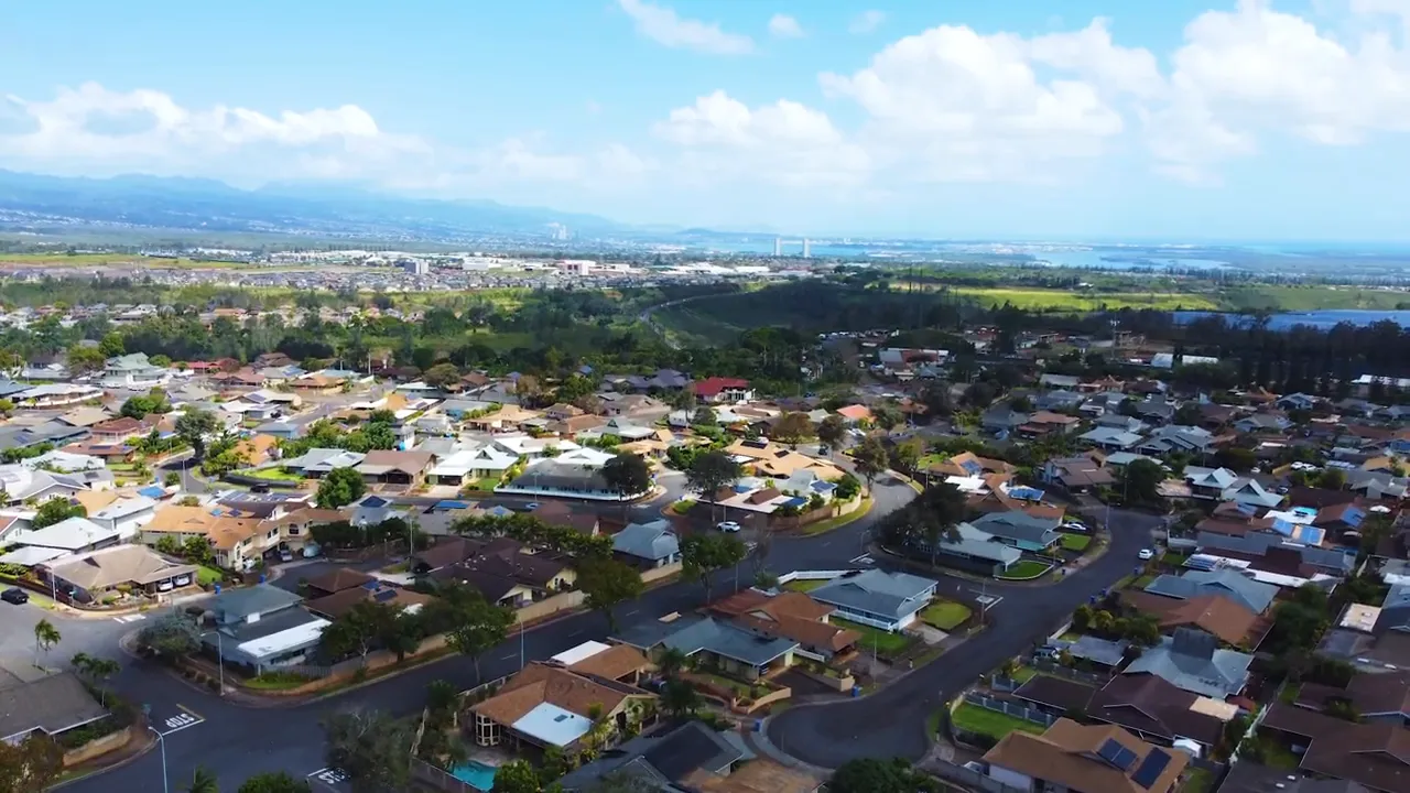 Aerial view of Mililani neighborhood with mountain ridges and coastline in the distance