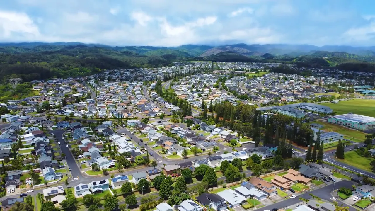 Wide aerial photograph of Mililani neighborhood layout with houses, streets and mountain ridges