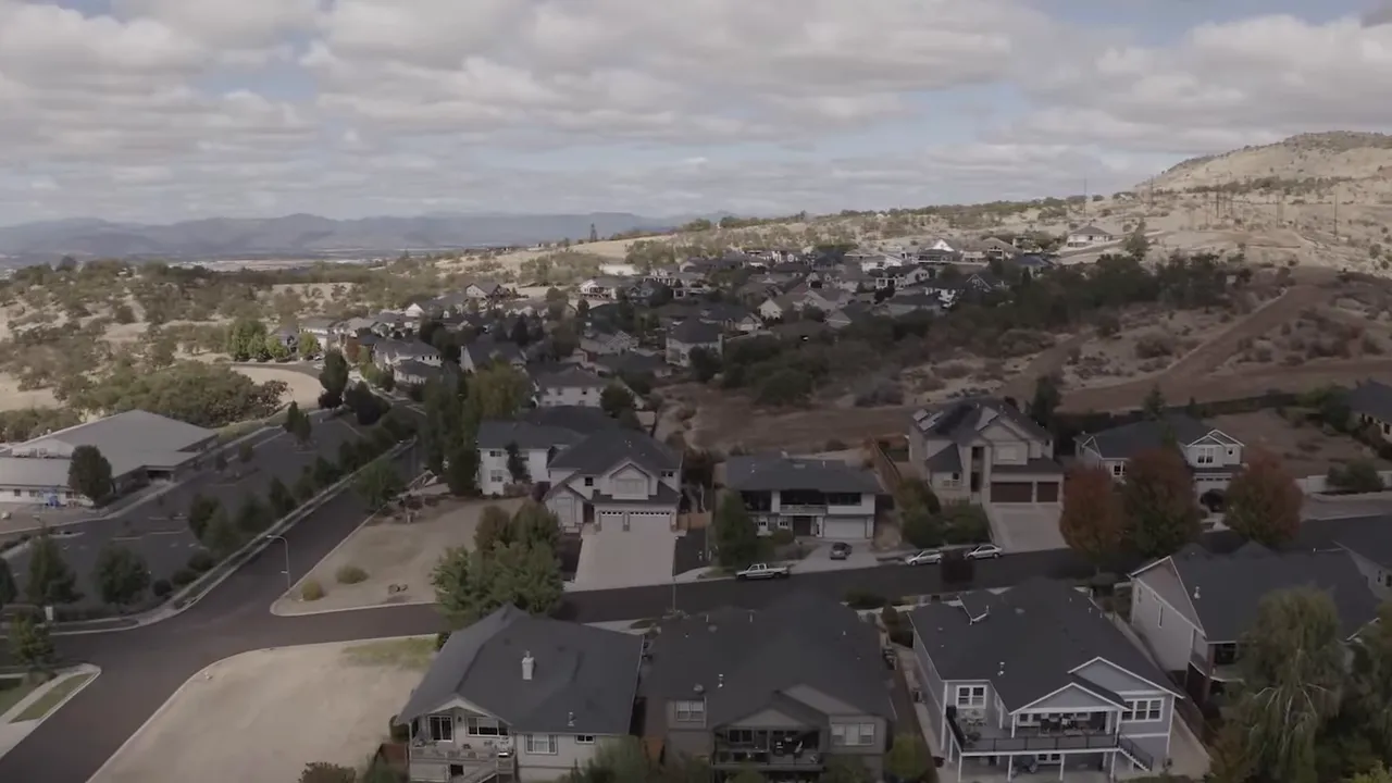Aerial drone view of a Southern Oregon neighborhood with houses, streets and rolling hills in the background