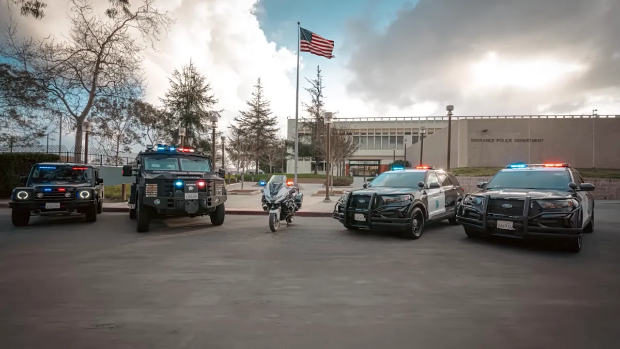Several Torrance police vehicles parked in front of a civic building with an American flag