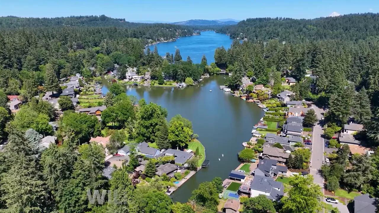 Aerial view of a lake-front residential neighborhood surrounded by dense forest, illustrating low-density interior Oregon housing and outdoor access.
