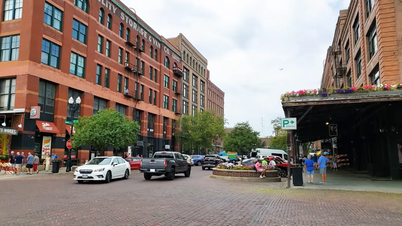 downtown Omaha street with brick road, mixed-use buildings, parked cars and pedestrians