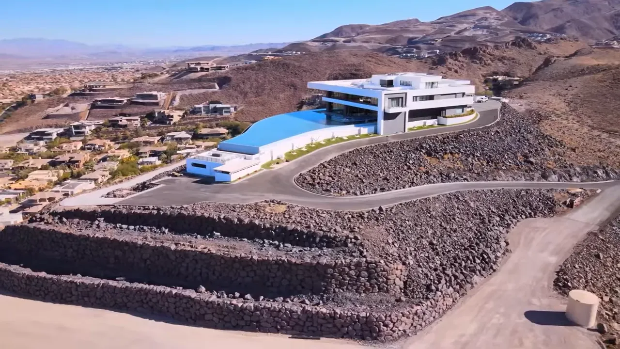 Modern white hillside home above dark volcanic rock terraces