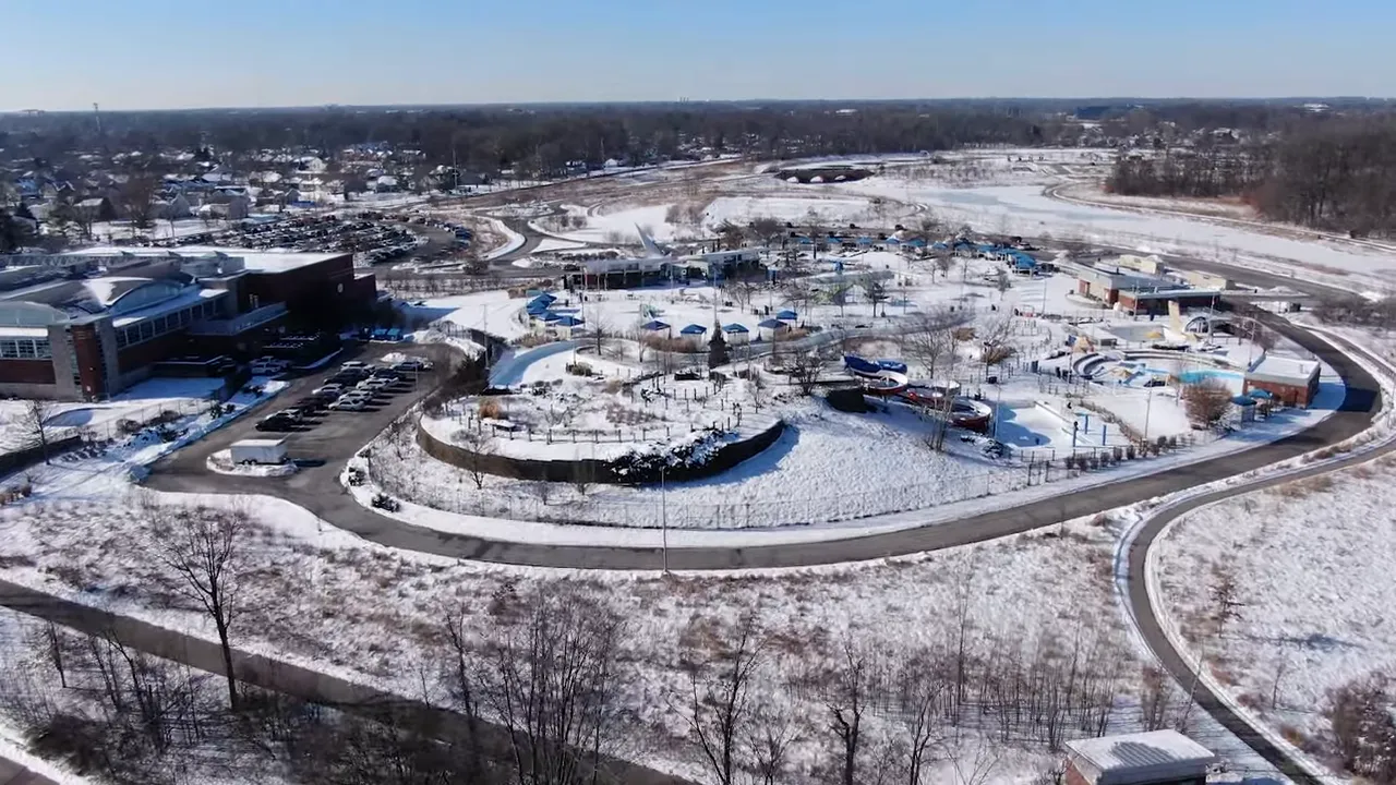 Crisp drone shot of a snowy water park with surrounding walking paths and open fields on a clear winter day